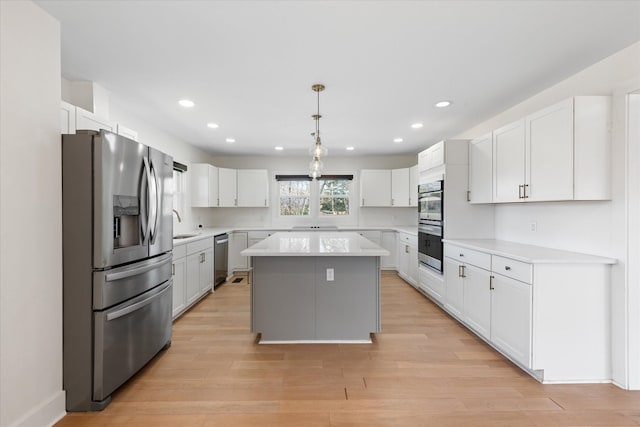 276 E Porters Bluff Rd E, Clarksville, TN 37040 - kitchen featuring light countertops, light wood finished floors, stainless steel appliances, white cabinetry, and a center island