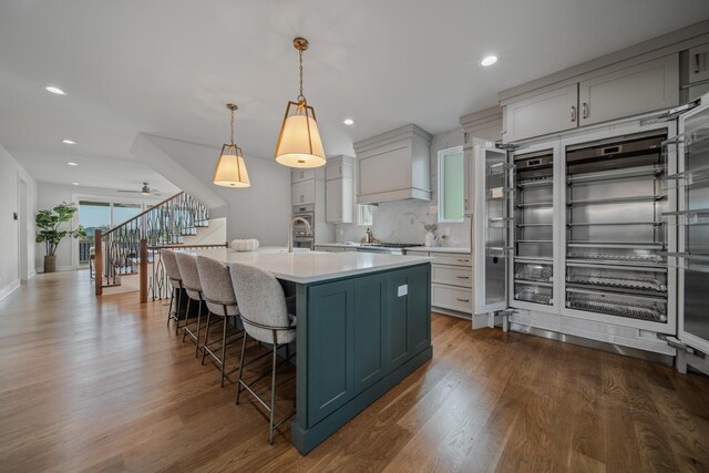 1405 Ashwood Ave, Nashville, TN 37212 - kitchen featuring custom exhaust hood, dark wood-style floors, light countertops, and a breakfast bar area