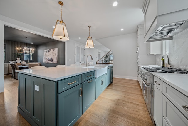 1405 Ashwood Ave, Nashville, TN 37212 - kitchen with custom range hood, light countertops, a center island with sink, light wood finished floors, and a sink