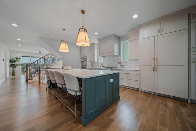 1405 Ashwood Ave, Nashville, TN 37212 - kitchen featuring a breakfast bar area, custom range hood, light countertops, and dark wood-style floors