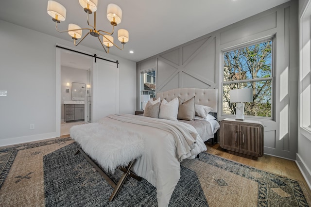1405 Ashwood Ave, Nashville, TN 37212 - bedroom featuring baseboards, an inviting chandelier, a barn door, a decorative wall, and wood finished floors