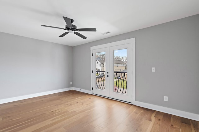 spare room featuring visible vents, baseboards, wood finished floors, a ceiling fan, and french doors