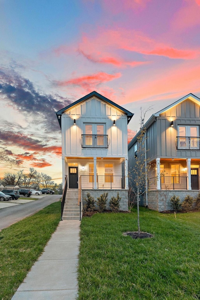 view of front of house featuring a balcony, a porch, board and batten siding, and a yard
