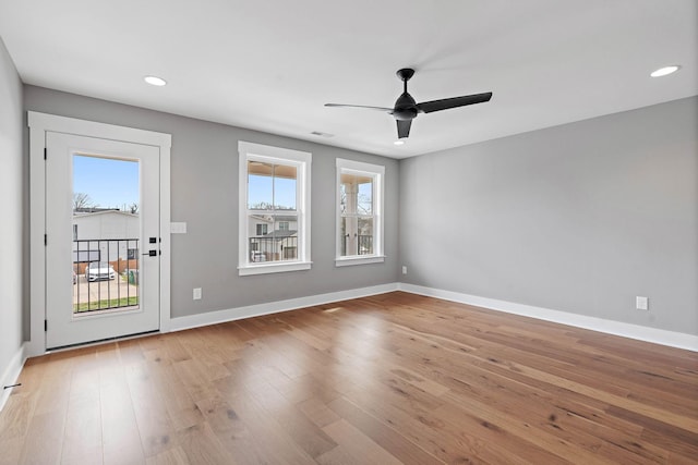 empty room with plenty of natural light, baseboards, light wood-style floors, and a ceiling fan