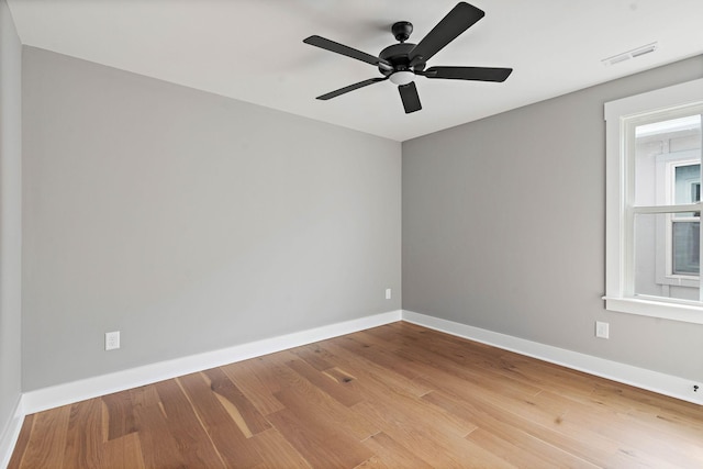 unfurnished room with baseboards, visible vents, wood finished floors, and a ceiling fan