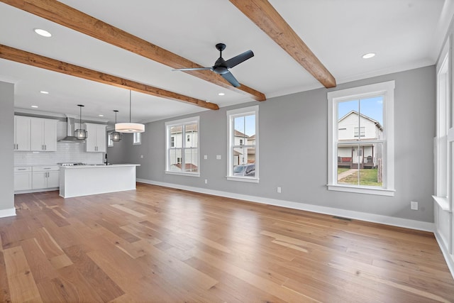unfurnished living room featuring baseboards, beam ceiling, light wood finished floors, ceiling fan, and visible vents
