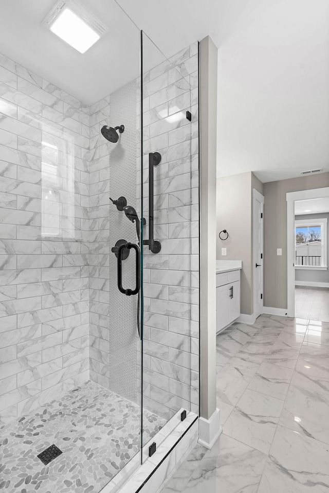bathroom featuring baseboards, marble finish floor, and a stall shower