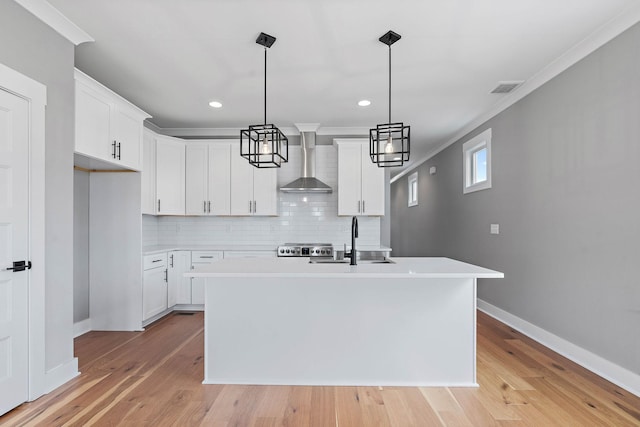 kitchen featuring light wood-style flooring, a sink, wall chimney exhaust hood, and light countertops
