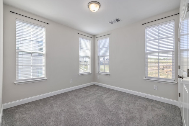 carpeted spare room with baseboards, a healthy amount of sunlight, and visible vents