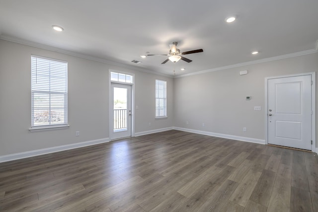 spare room featuring dark wood-style flooring, crown molding, a ceiling fan, and plenty of natural light