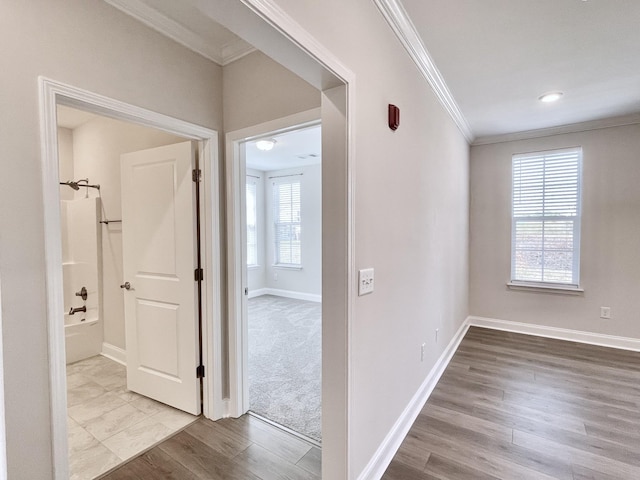 corridor with ornamental molding, baseboards, and wood finished floors