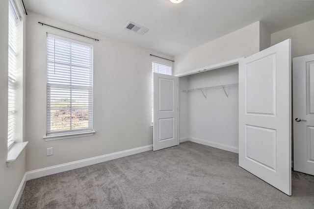 unfurnished bedroom with multiple windows, visible vents, carpet floors, and baseboards