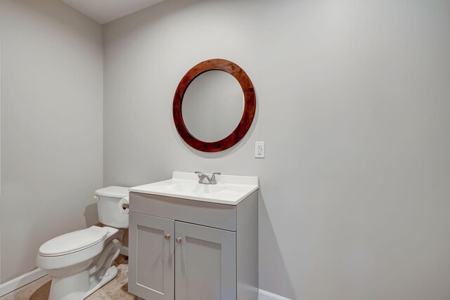 bathroom with baseboards, toilet, and vanity
