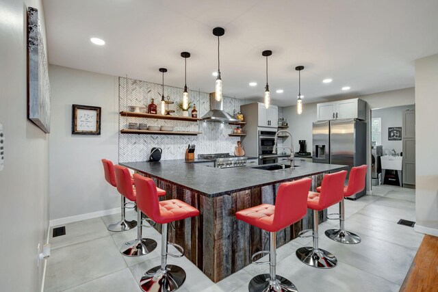 kitchen featuring stainless steel appliances, dark countertops, decorative backsplash, wall chimney range hood, and open shelves