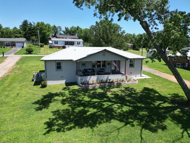back of property featuring a porch, a yard, and metal roof