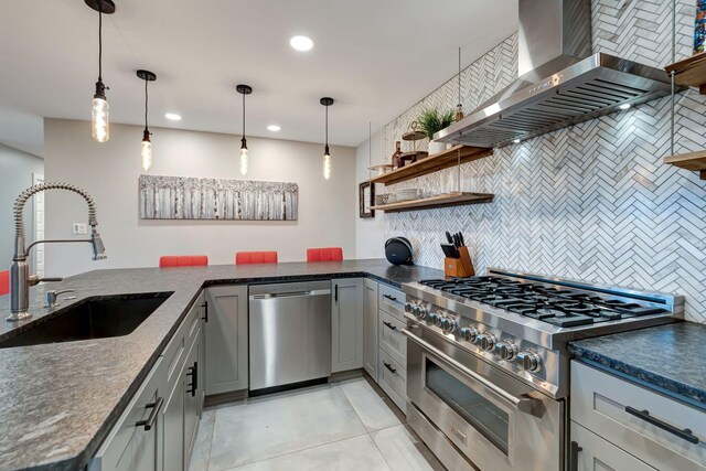 kitchen featuring wall chimney exhaust hood, stainless steel appliances, a sink, tasteful backsplash, and gray cabinets