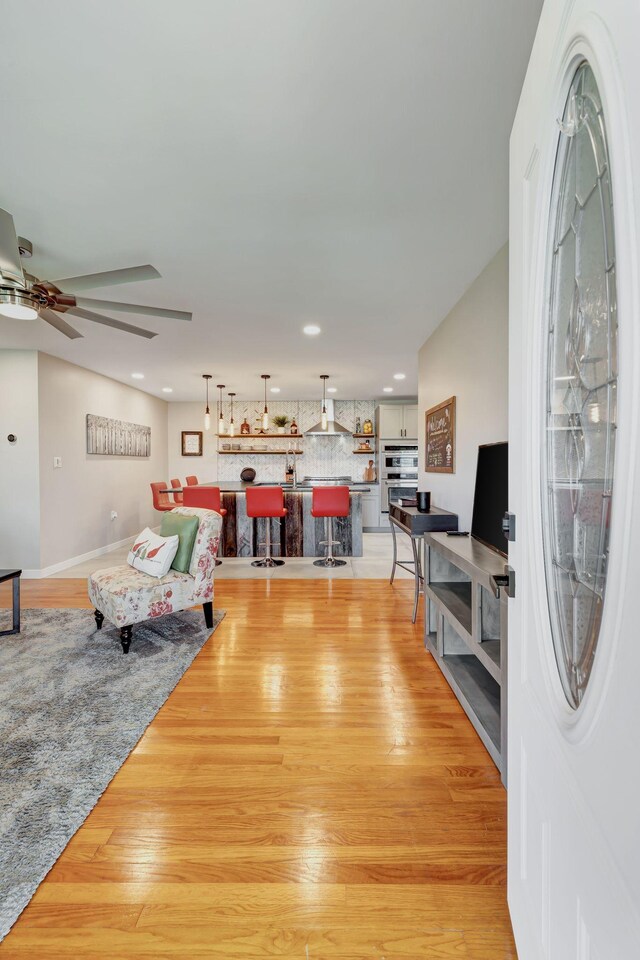 living area with recessed lighting, a ceiling fan, and light wood-type flooring