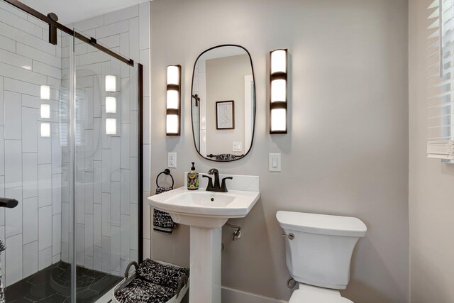 bathroom with toilet, a stall shower, and a sink