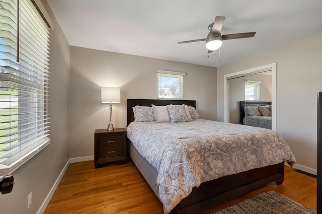 bedroom with light wood finished floors, a ceiling fan, baseboards, and a closet