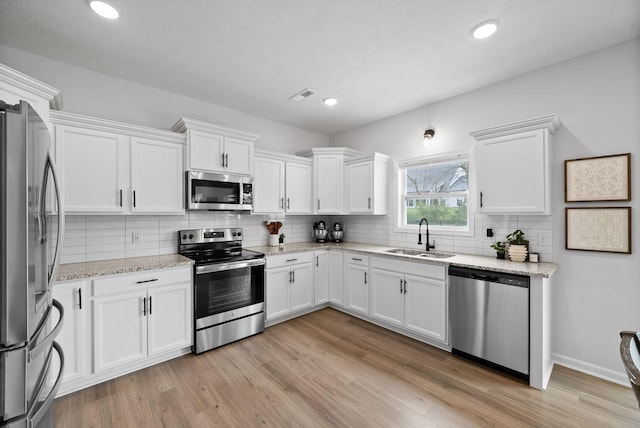 221 Wesson Dr, Clarksville, TN 37043 - kitchen with white cabinets, light wood-style flooring, a sink, and stainless steel appliances