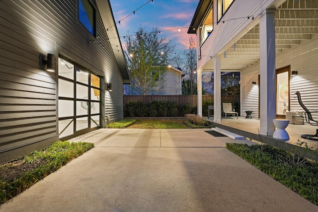924 Gilmore Ave, Nashville, TN 37204 - patio terrace at dusk featuring a garage, fence, and concrete driveway