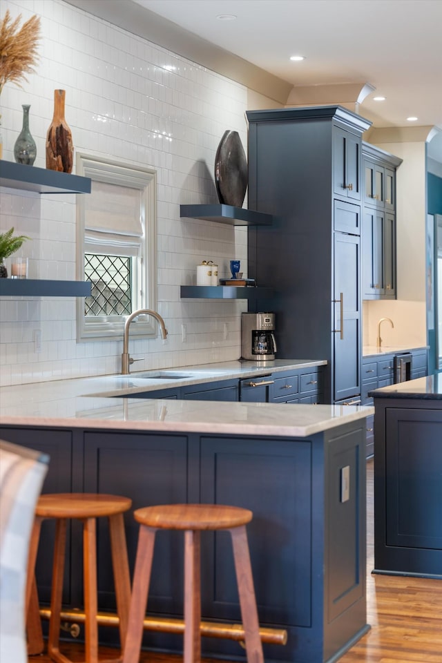 924 Gilmore Ave, Nashville, TN 37204 - kitchen featuring a breakfast bar area, blue cabinets, open shelves, and tasteful backsplash