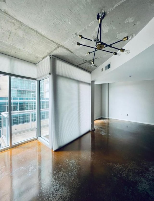 unfurnished room featuring finished concrete flooring, baseboards, a chandelier, and visible vents