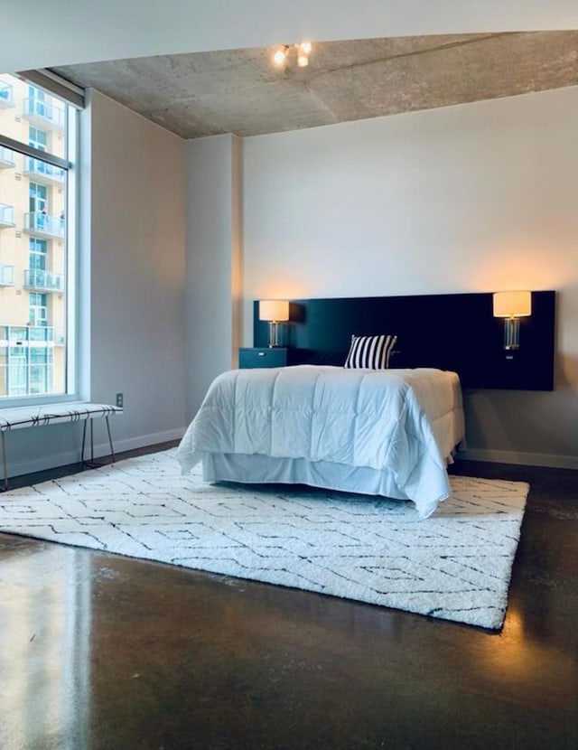 bedroom with baseboards, concrete floors, and multiple windows