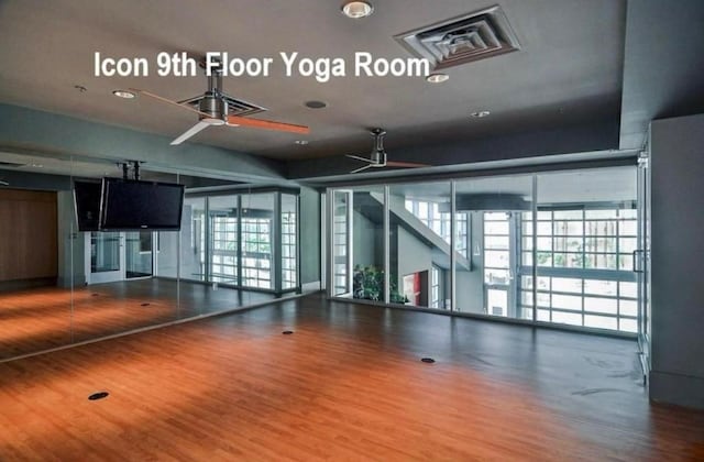 workout room featuring wood finished floors, expansive windows, and visible vents