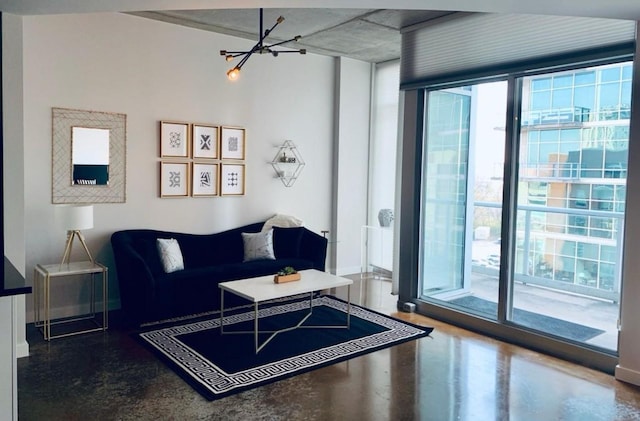 living area with a chandelier, concrete flooring, baseboards, and expansive windows