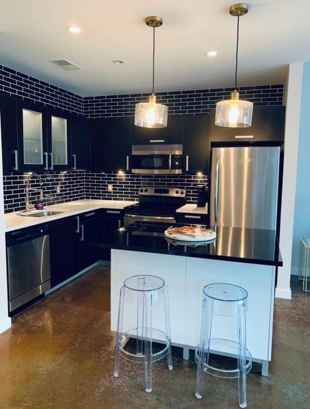 kitchen with backsplash, a sink, a breakfast bar area, glass insert cabinets, and stainless steel appliances