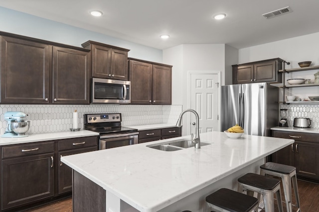 1424 Old Stone Rd NW, Lebanon, TN 37087 - kitchen with dark brown cabinetry, a sink, a breakfast bar, stainless steel appliances, and visible vents
