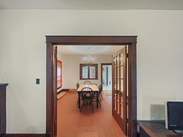 dining area with baseboards, a notable chandelier, and hardwood / wood-style flooring