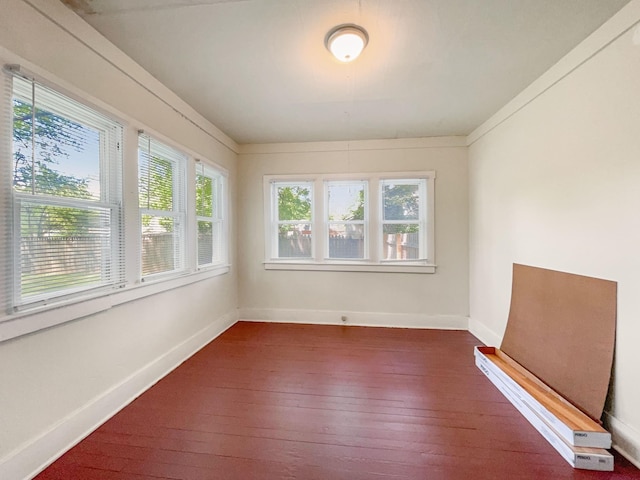 empty room with a wealth of natural light, baseboards, and dark wood-type flooring