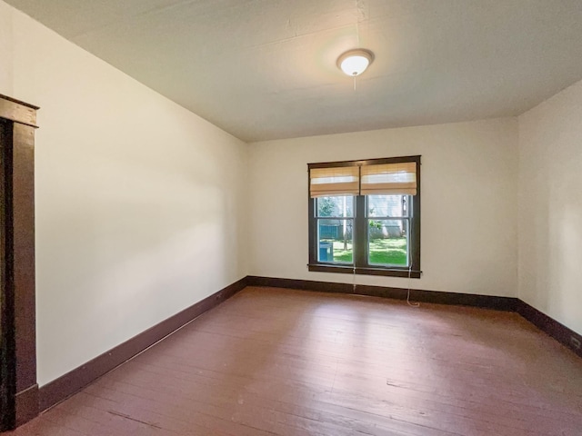 unfurnished room featuring baseboards and wood-type flooring