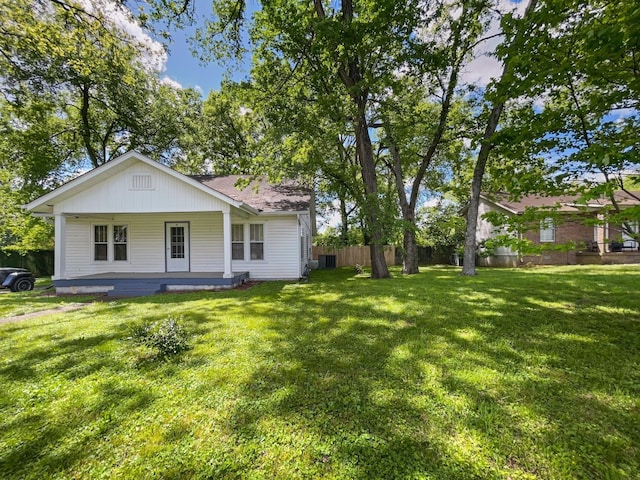 back of house with cooling unit, covered porch, fence, and a yard