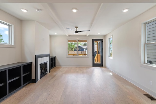 unfurnished living room featuring a ceiling fan, light wood-style flooring, a fireplace, baseboards, and visible vents