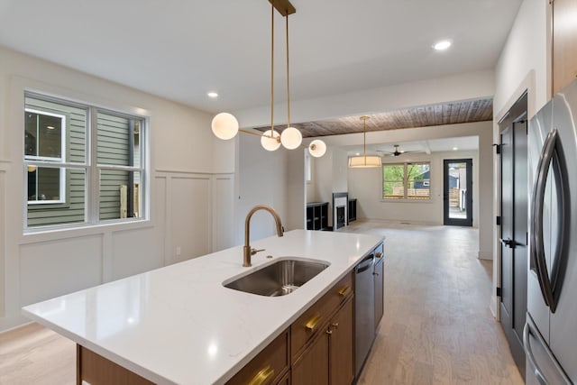 kitchen featuring light wood-style floors, appliances with stainless steel finishes, open floor plan, and a sink