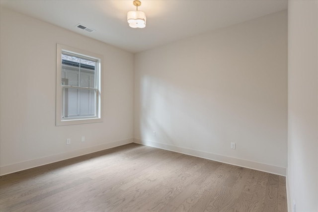 spare room featuring baseboards, visible vents, and light wood-style flooring