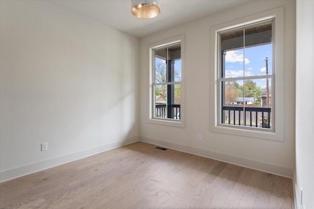 spare room with visible vents, baseboards, and wood finished floors