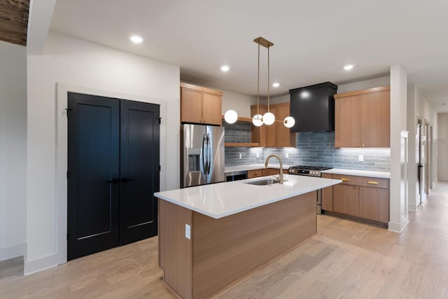 kitchen featuring a sink, premium range hood, light wood-type flooring, decorative backsplash, and appliances with stainless steel finishes