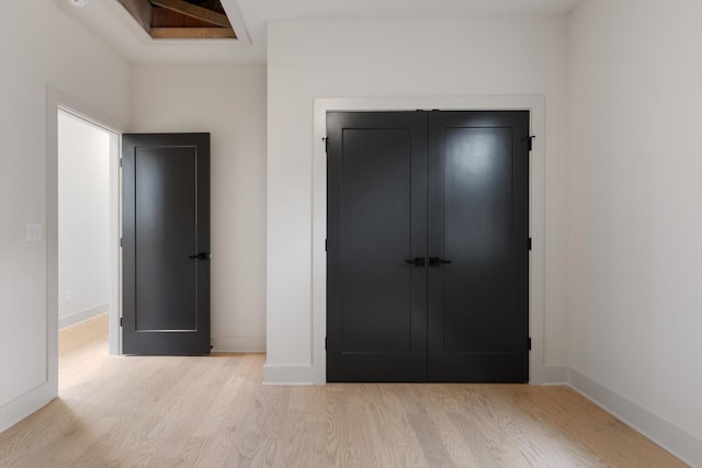 unfurnished bedroom featuring baseboards, wood finished floors, and a closet