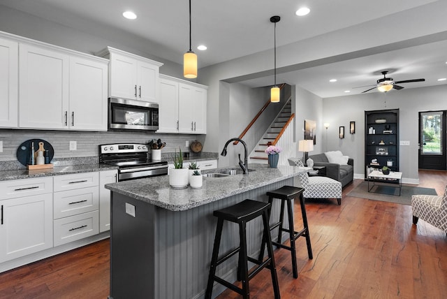 kitchen featuring open floor plan, dark wood-style flooring, a sink, and stainless steel appliances