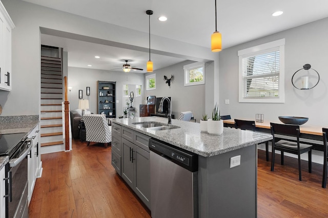 kitchen with stainless steel appliances, dark wood finished floors, a sink, open floor plan, and gray cabinets