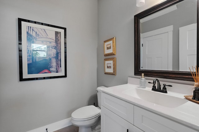 bathroom featuring toilet, vanity, and baseboards