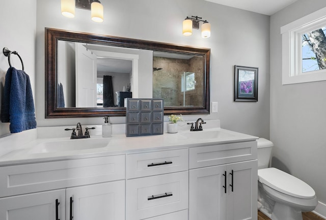 bathroom featuring toilet, a sink, a stall shower, and double vanity