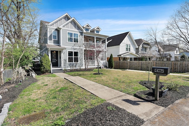view of front facade featuring a balcony, fence, board and batten siding, and a front yard