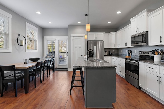 kitchen with tasteful backsplash, stainless steel appliances, dark wood-type flooring, a sink, and white cabinets