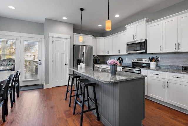 kitchen with tasteful backsplash, a sink, dark wood-style floors, white cabinets, and appliances with stainless steel finishes