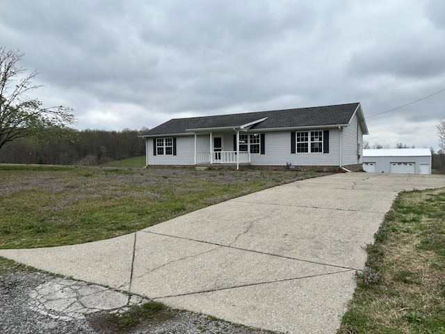 single story home featuring a porch, an outbuilding, driveway, and a front lawn